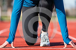 Man athlete on the starting line of a running track at the stadium, close up.