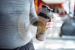 Man athlete took a break in training and drinking water, with a sports bottle in the gym