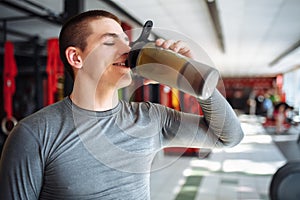 Man athlete took a break in training and drinking water, with a sports bottle in the gym