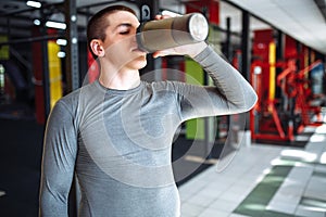 Man athlete took a break in training and drinking water, with a sports bottle in the gym