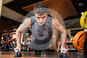 Man athlete training and doing push-ups in gym