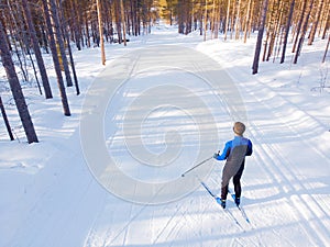 Man athlete trains cross-country skiing in winter on snow covered track in forest