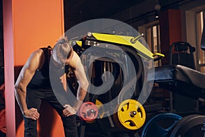 A man of athletic build tiredly leaned against the wall after exercising in the gym