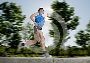 Man with athletic legs running in city park with trees on the background on summer training session fitness healthy lifestyle