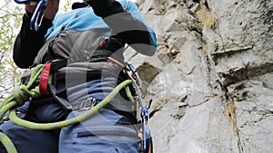 Man athlette with carabine and rope near rock