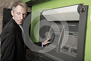 Man at an atm maching glancing over his shoulder