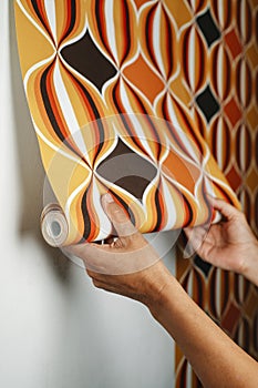 man attaches a geometric wallpaper to the wall