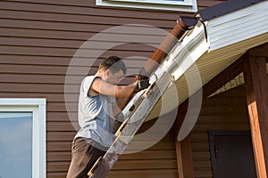 Man attaches gutter on roof of porch