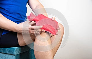A man attaches a medical heating pad with hot water to his knee. Treatment of knee sprains, pain and inflammation photo