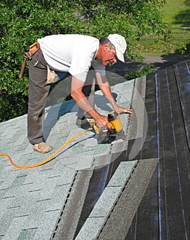 Man attaches shingles to roof