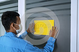 Man attaching closed sign on the company door