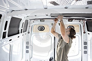 Man attaching thermal insulation in a camper van