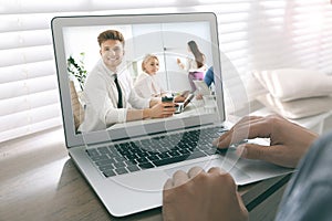 Man attending online video conference via modern laptop at table, closeup