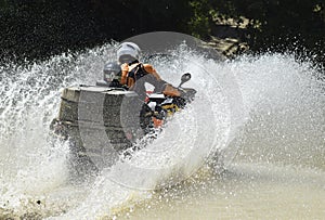 The man on the ATV crosses a stream