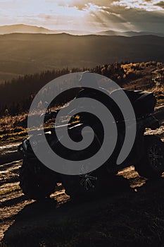 Man on ATV is driving offroad in mountains during autumn sunset time