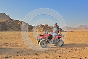 Man ATV rider on a desert with mountains view