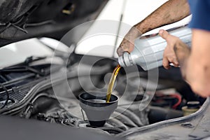 Man auto mechanic repairs car in autoservice, station. Changes oil