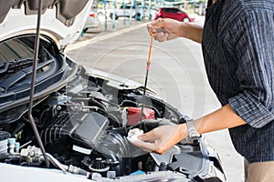 Man or auto mechanic worker checking the car engine oil and maintenance before traveling for safety