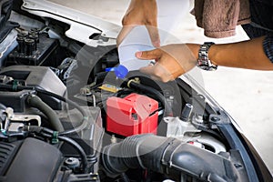 Man or auto mechanic worker hands add distilled water to car battery. Checking and maintenance service the car battery