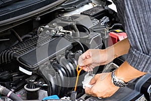 Man or auto mechanic worker hands checking the car engine oil and maintenance before traveling for safety