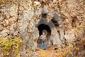 Man in autumnal park near cavern