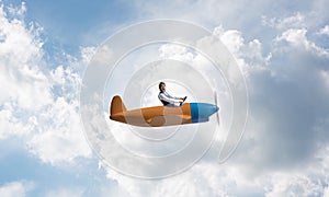 Man in aviator hat driving propeller plane