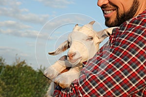 Man with baby goat at farm, closeup. Animal husbandry