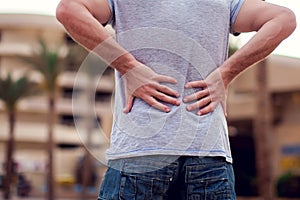Man with back pain sitting on bench at the outdoor. People, health care and medicine concept