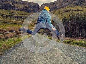 Man back to camera jumping in the air, stunning nature scenery in the background. Light motion blur on the model. Gleniff horse