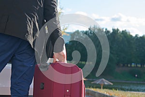 man on the background of autumn, loads the Luggage-suitcase in the car