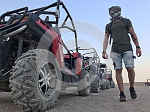 The man on the background of a sports car is buggy. ATV desert tour in Egypt. Outdoor activities and adventures in the stone