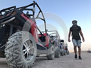 The man on the background of a sports car is buggy. ATV desert tour in Egypt. Outdoor activities and adventures in the stone