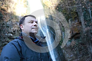 Man on background of waterfall