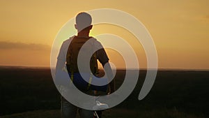 A man with a backpack and a bicycle. It stands and looks at the horizon where the sun sets. Cycling and adventure