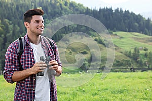 Man with backpack and binoculars in mountains