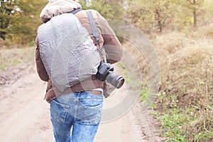 Man with a backpack and camera going to forest