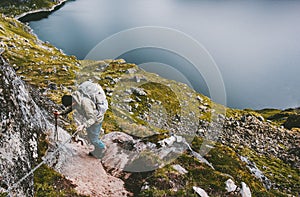 Man with backpack climbing up holding chains to mountain summit