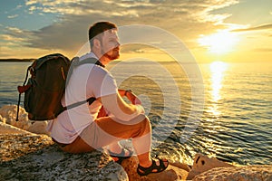 man with backpack enjoying sunset over the sea