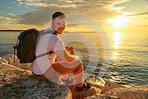 man with backpack enjoying sunset over the sea