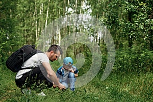 A man with a backpack, a father and his son on a hike, walking during walks in the woods. Family life, pastime with the family,