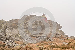 A man with a backpack for a hike climbs to the top of the mountain on a rocky path, a tourist hike in the Carpathians in