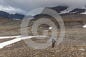 Man backpack hiker at Kungsleden trail admiring nature of Sarek in Sweden Lapland with mountains, rivers and lakes, birch and