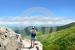 Man with backpack hiking in mountains on a summer vacation trip.