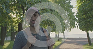 A man with a backpack is leisurely standing in the park