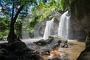 Man with backpack looking at scenic waterfall in Thailand