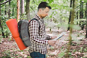 Man with Backpack and map searching directions in wilderness area. Tourist with backpack using map in forest. concept