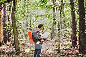 Man with Backpack and map searching directions in wilderness area. Tourist with backpack using map in forest. concept