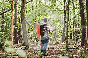 Man with Backpack and map searching directions in wilderness area. Tourist with backpack using map in forest. concept