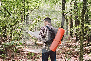 Man with Backpack and map searching directions in wilderness area. Tourist with backpack using map in forest. concept