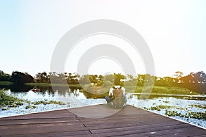 Man with backpack sitting alone on the edge of pond pondering an